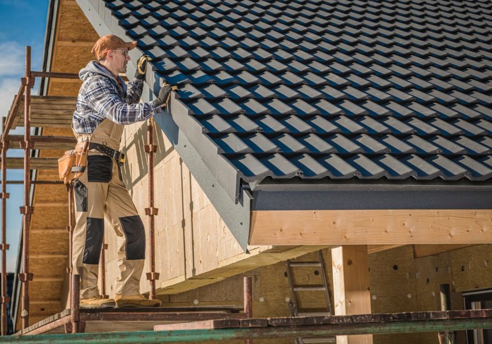 Finishing Ceramic Roof Professional Roofer Worker Finishing Ceramic Roof Tiles Installation. Smiling and Happy Worker on a Scaffolding.